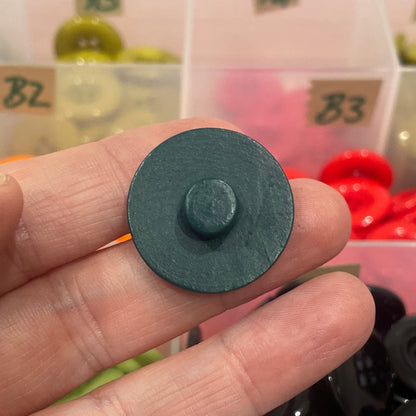 Person holding a button with a container of buttons in the background