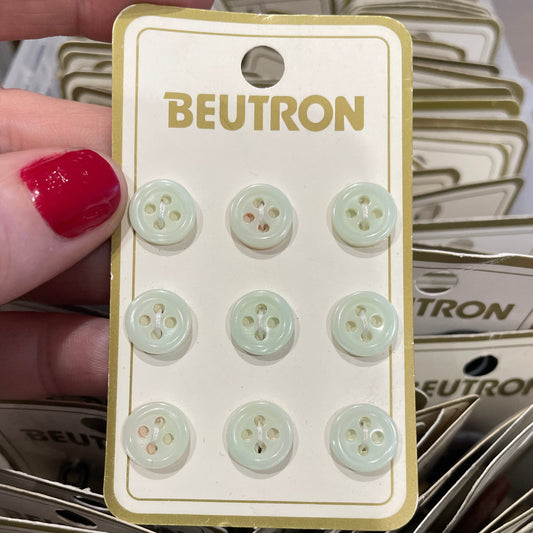 Card with light green buttons held by a hand against a background of similar cards.