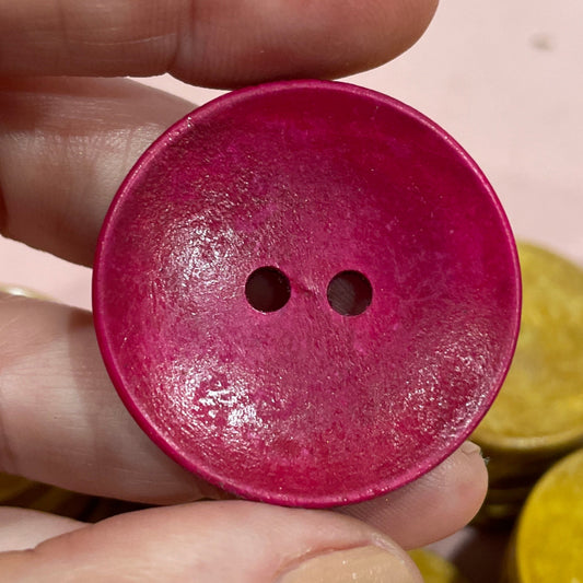 Hand holding a pink button with other buttons in the background
