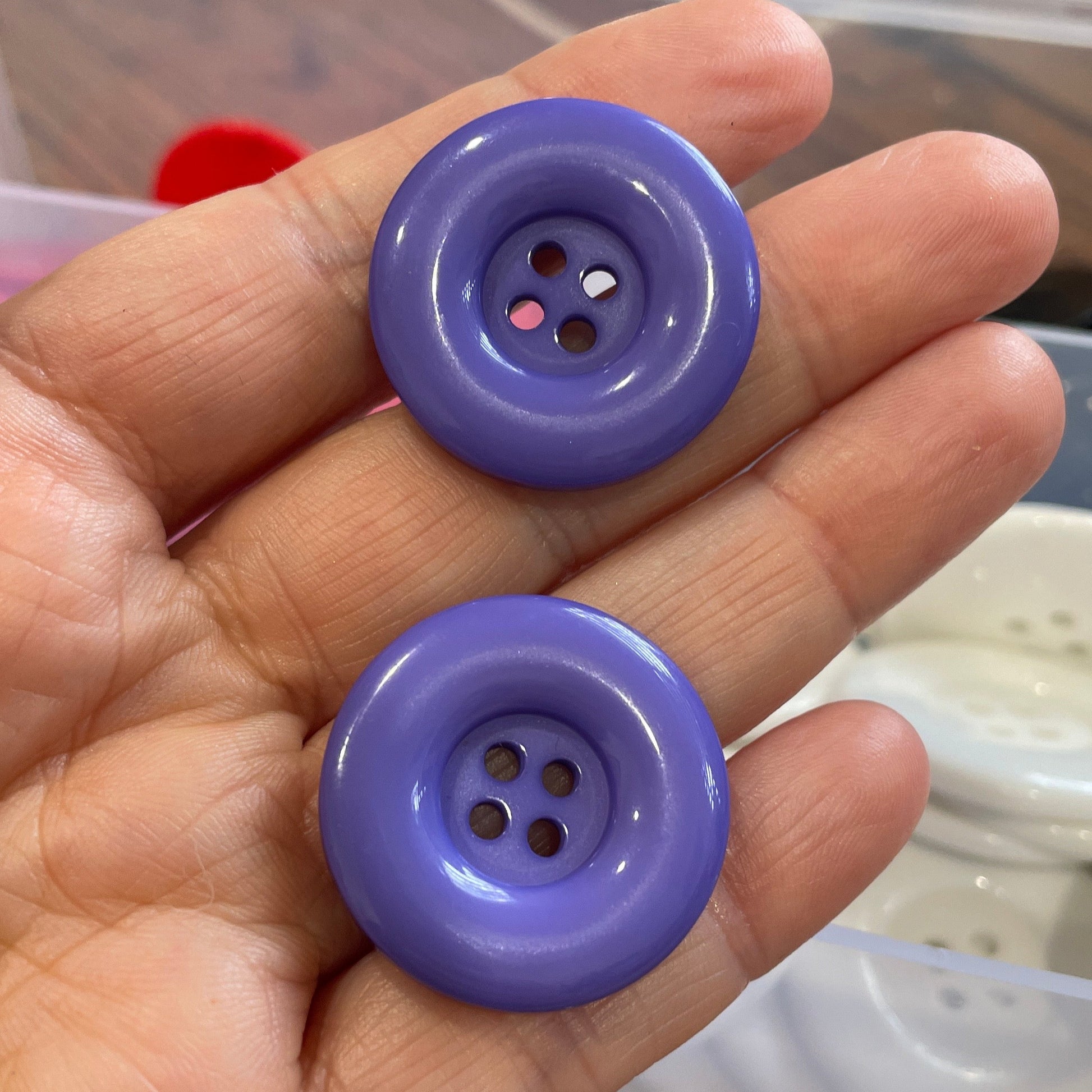 Two purple buttons held in a hand with a blurred background