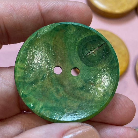 Hand holding a green button with other colorful buttons in the background