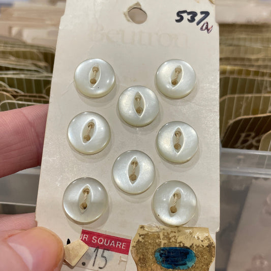 Set of pearl buttons on a card held by a hand with a blurred background