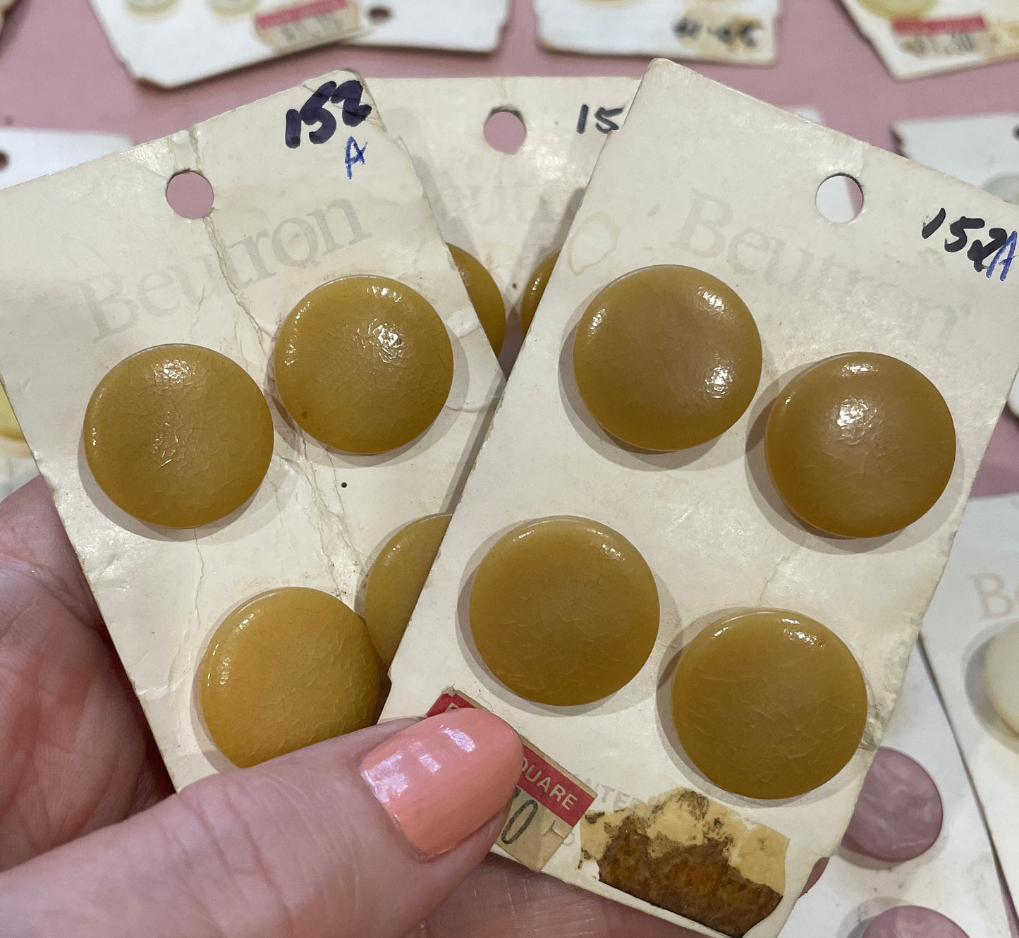 Hand holding a package of round, brown buttons