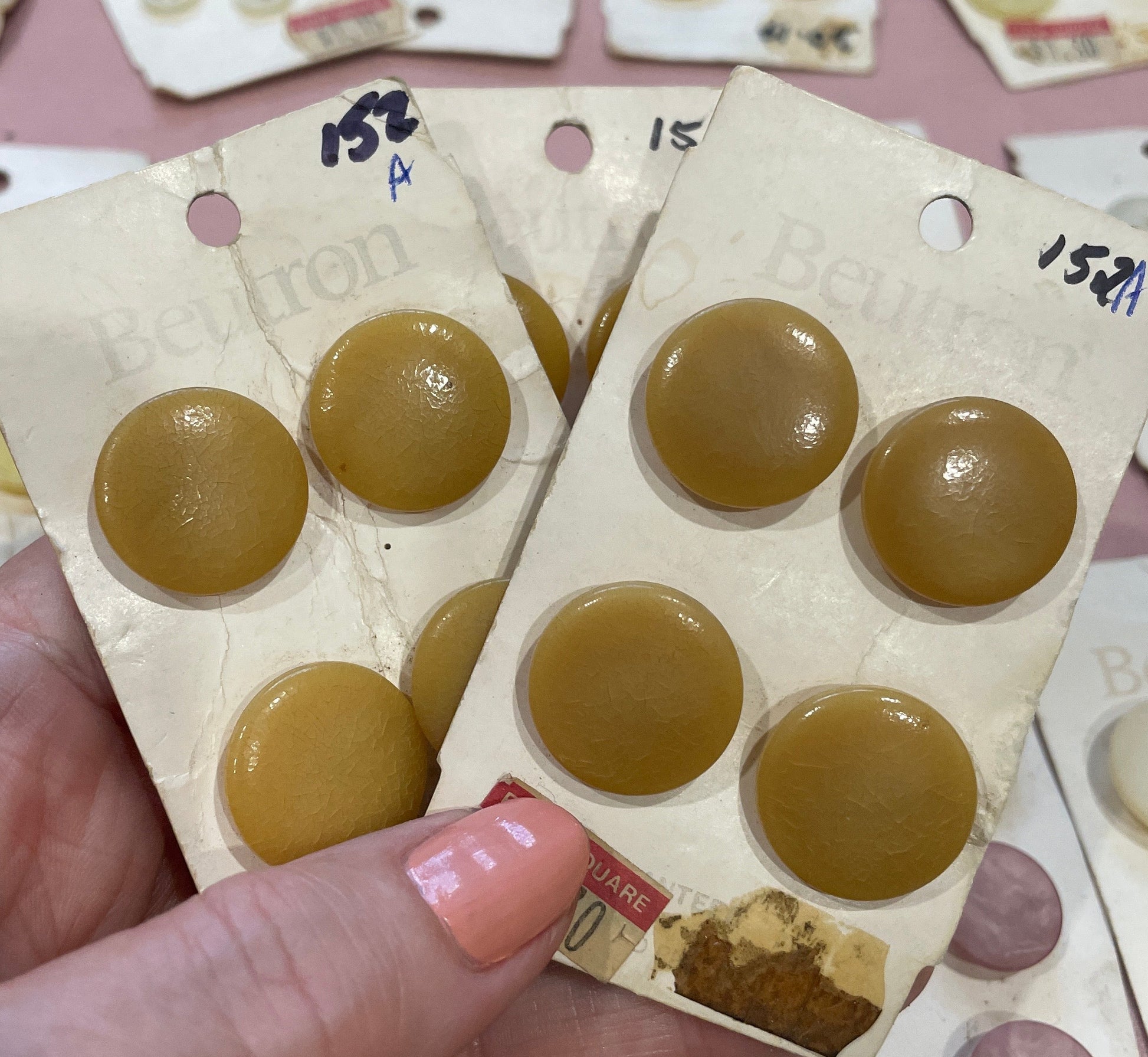Hand holding a package of round, brown buttons