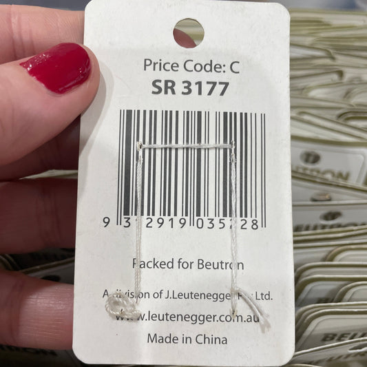 Close-up of a product tag with a barcode and text, held by a hand.