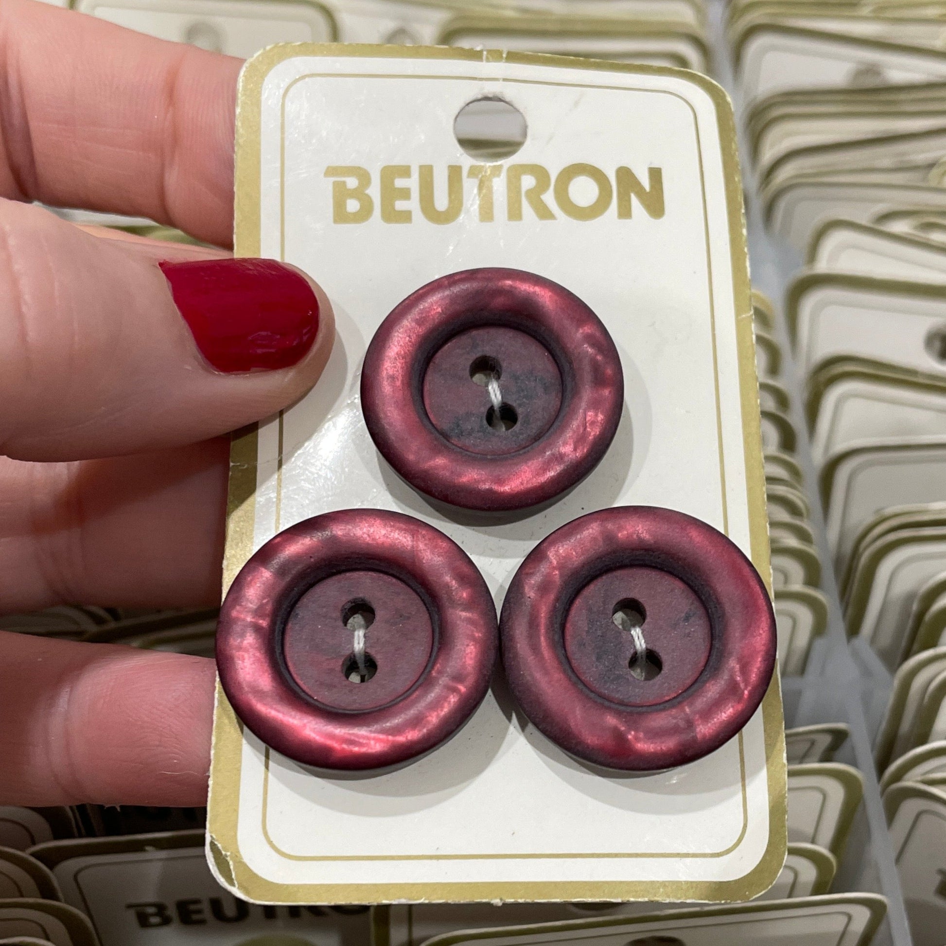 Hand holding a card with red buttons against a background of similar cards.