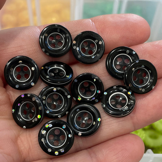 Hand holding black buttons with a blurred background of button containers.