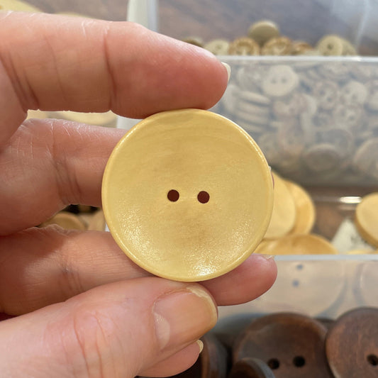 Hand holding a Button with a container of buttons in the background