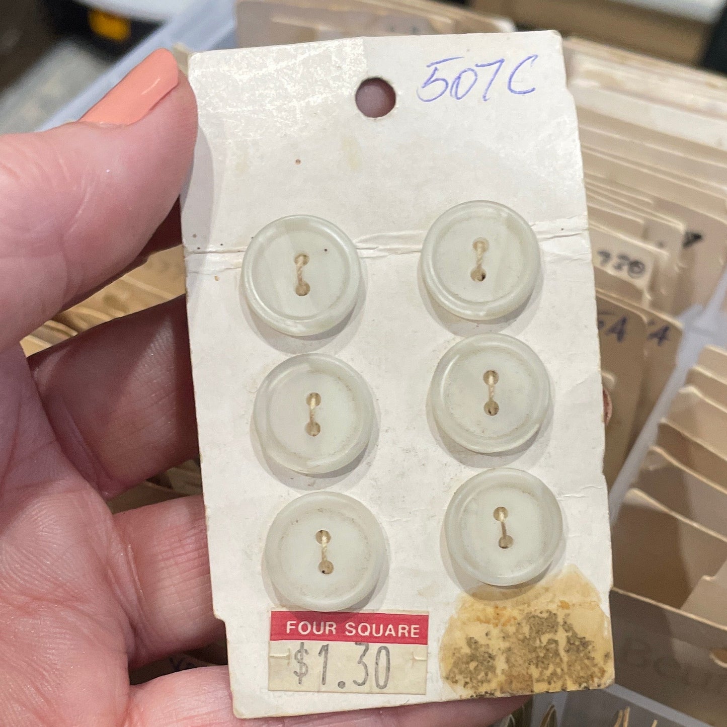 Hand holding a card with vintage buttons in front of a collection of similar cards.