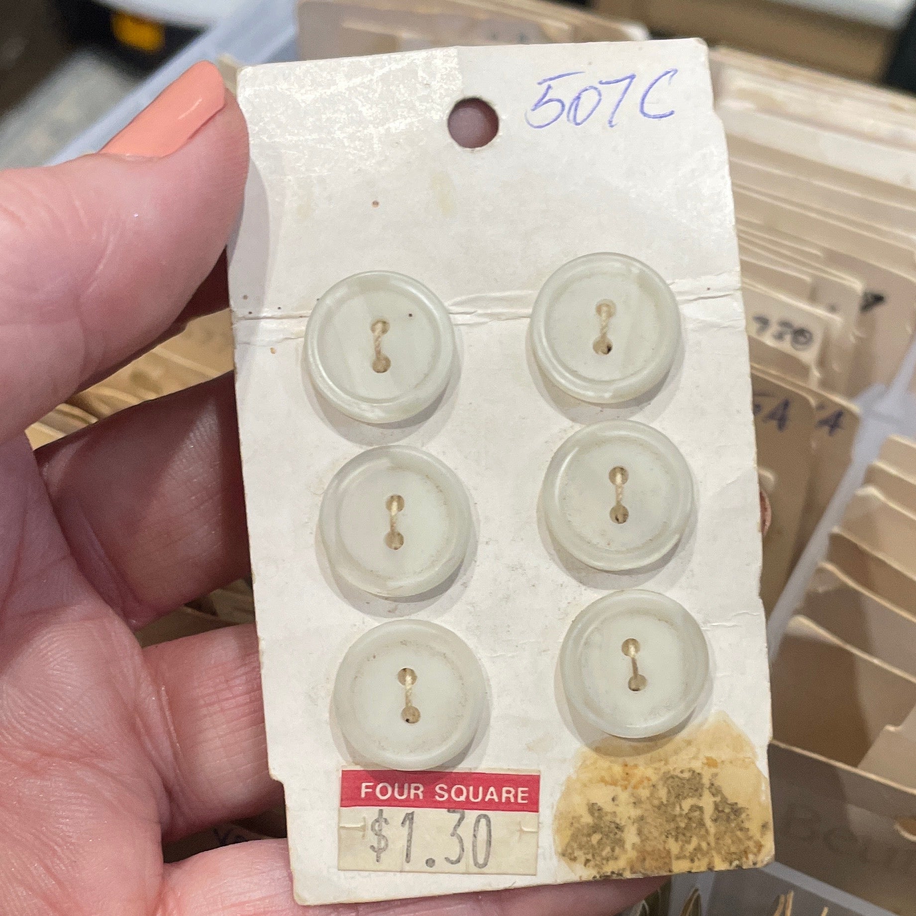 Hand holding a card with vintage buttons in front of a collection of similar cards.