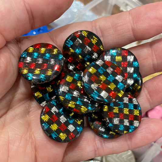 Hand holding colorful buttons with a container of various buttons in the background