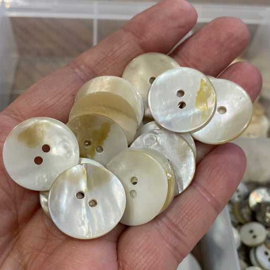 Hand holding a collection of white buttons with a blurred background