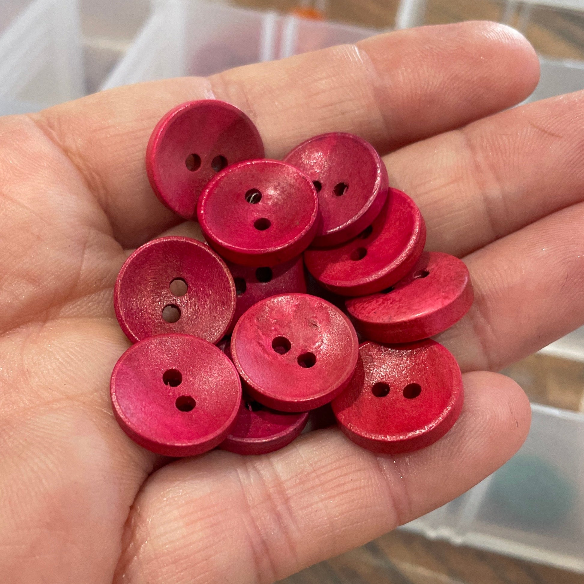 Hand holding red buttons with a blurred background of a storage box.