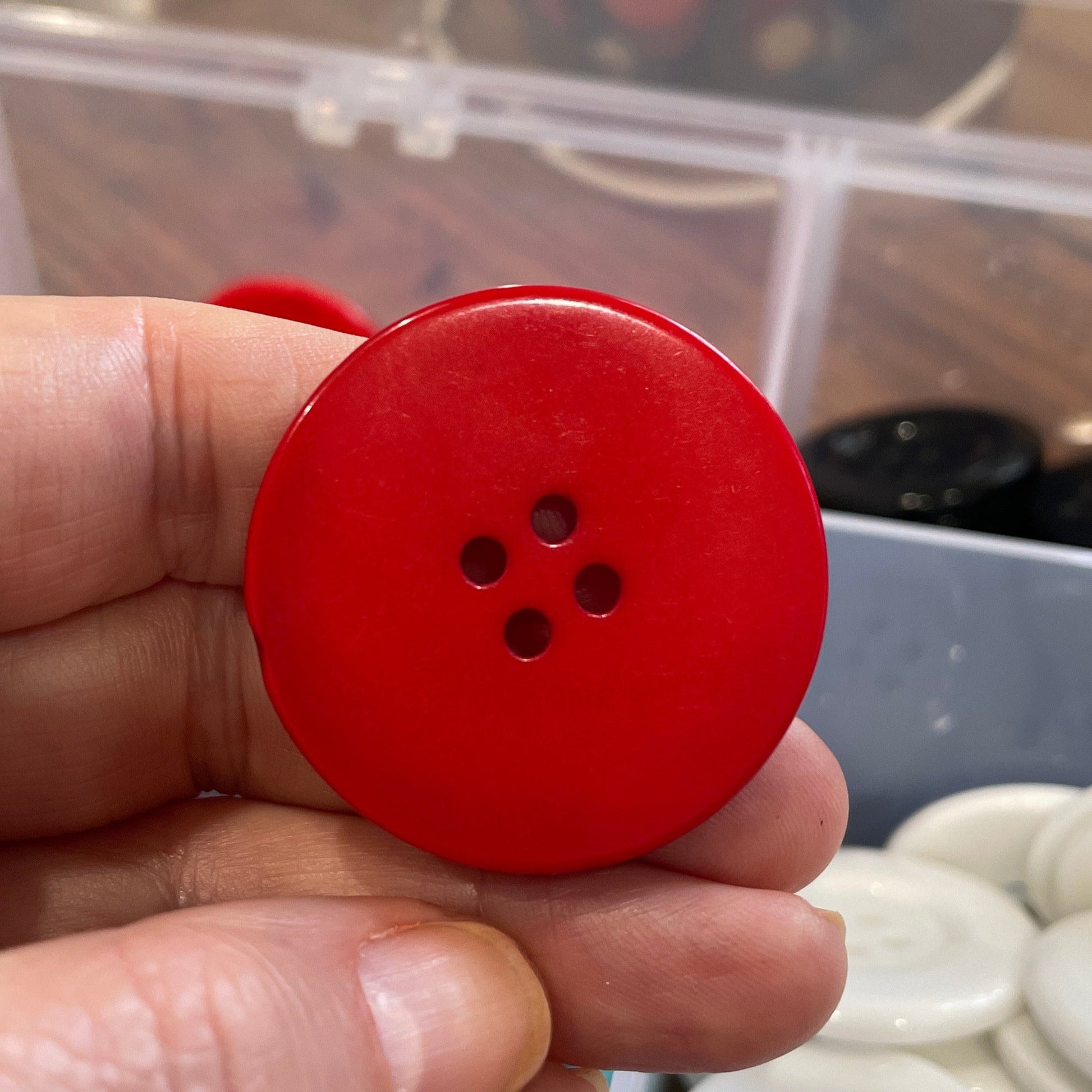Red button held in a hand with a blurred background