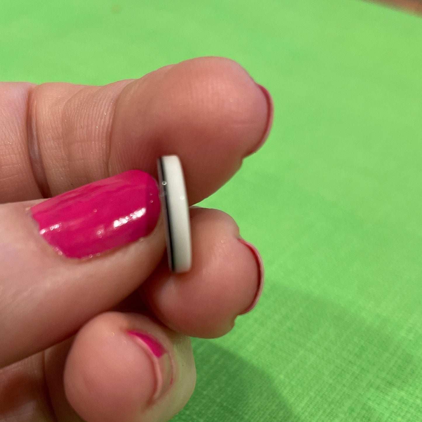 Small white object held between fingers against a green background