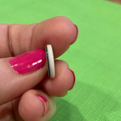 Small white object held between fingers against a green background