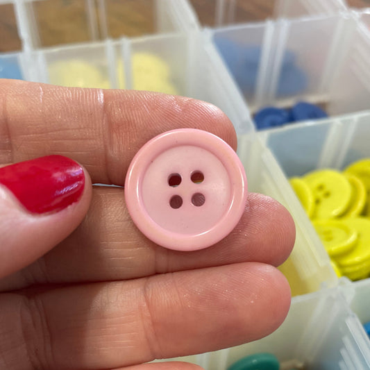 Pink button held between fingers with colorful buttons in the background