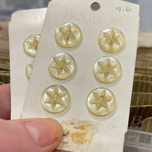 Gold buttons on a card held by a hand with a blurred background