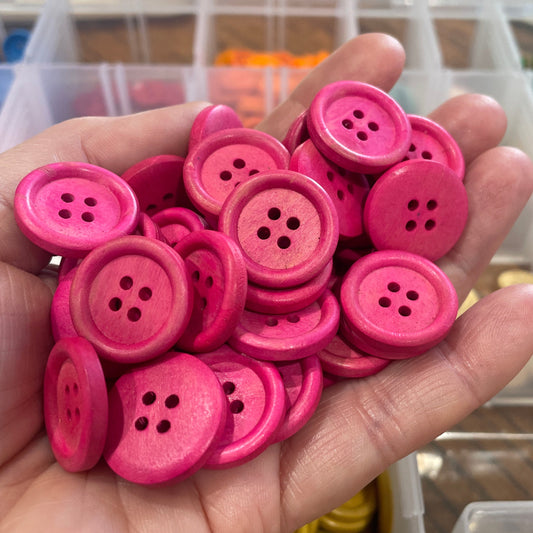 Hand holding pink buttons with a blurred background