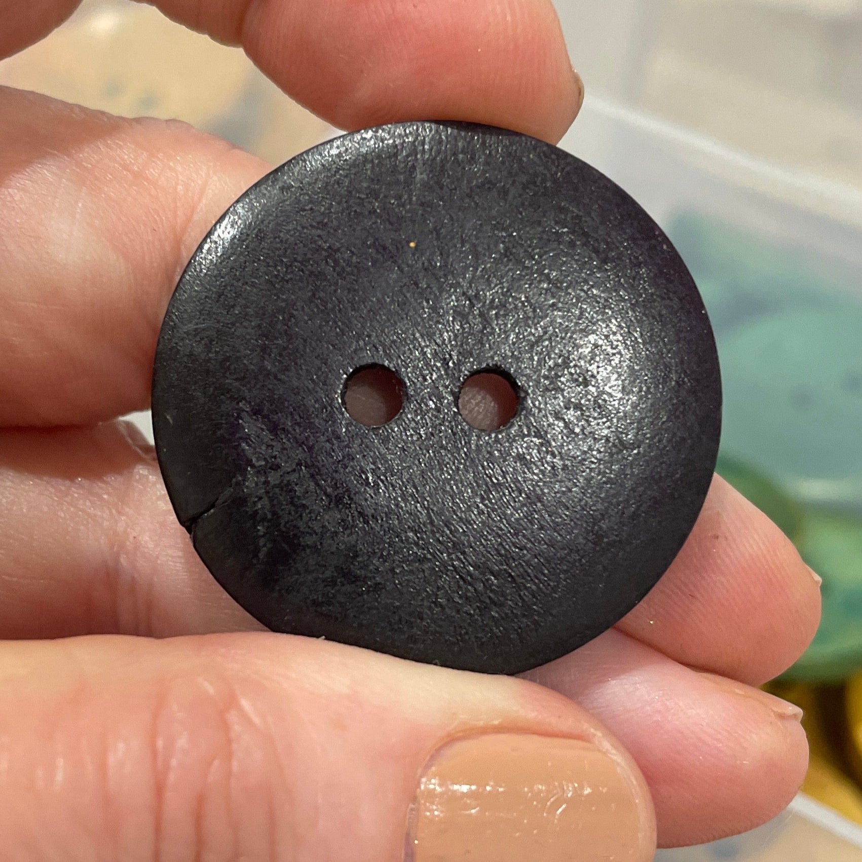Hand holding a black button with a blurred background of buttons