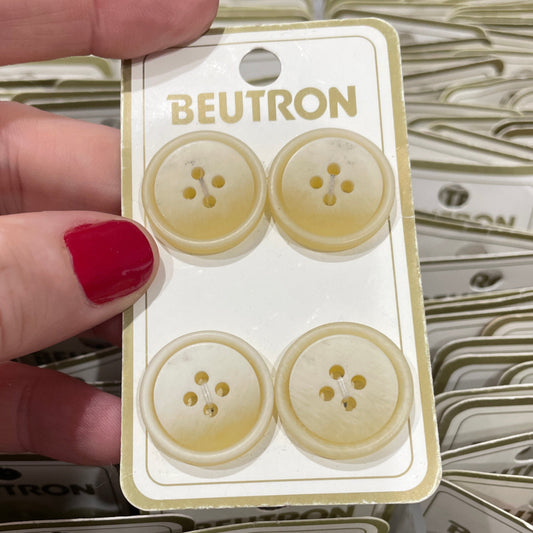 Hand holding a package of Beutron buttons with a blurred background