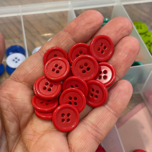Hand holding red buttons with a container of buttons in the background
