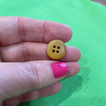 Yellow button held between fingers against a green background