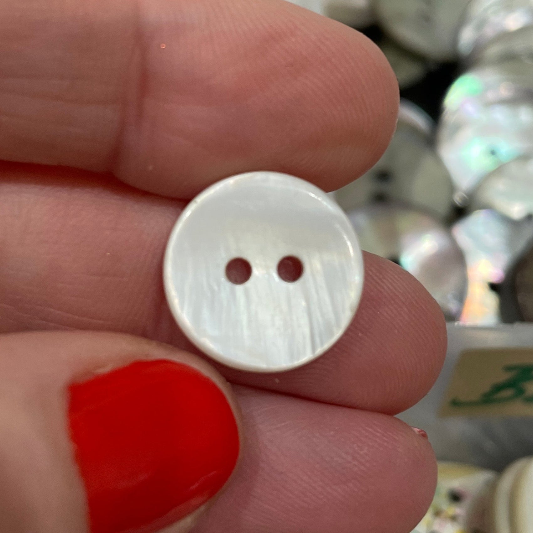 White button held between two fingers with a blurred background of various buttons