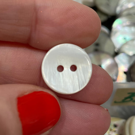 White button held between two fingers with a blurred background of various buttons