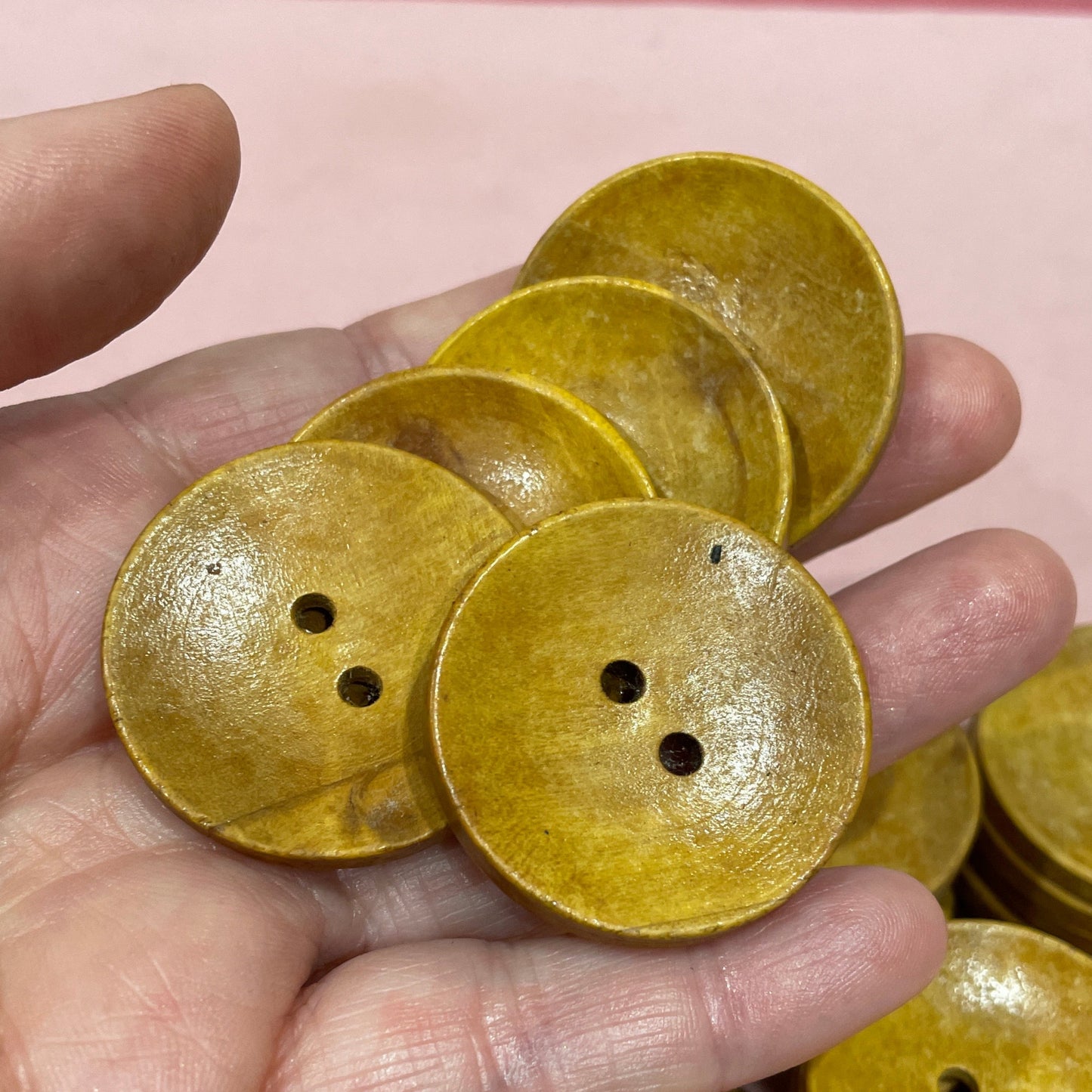Hand holding yellow buttons with a pink keyboard in the background
