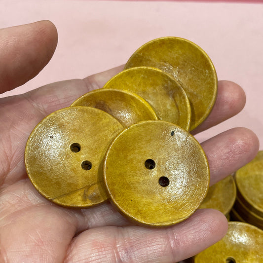 Hand holding yellow buttons with a pink keyboard in the background