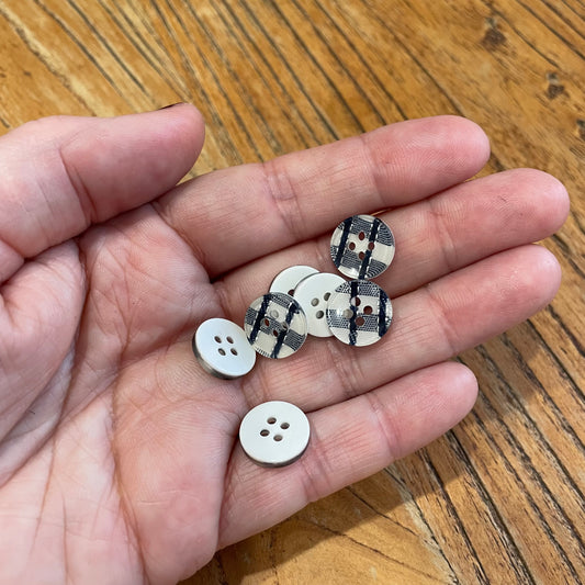 Hand holding small buttons with a wooden surface background