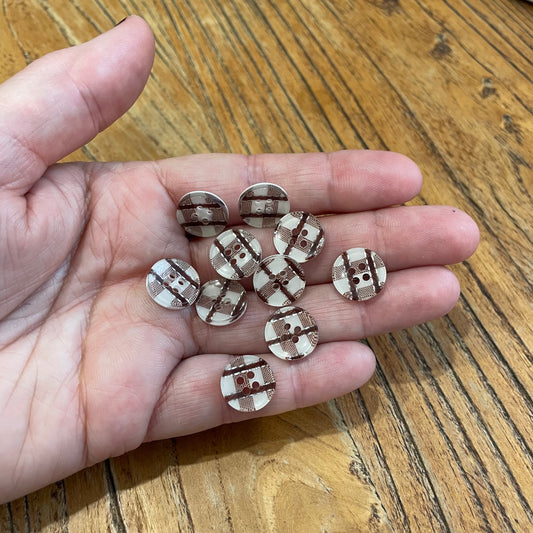 Hand holding a small pile of decorative buttons on a wooden surface