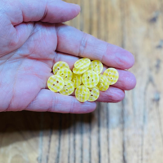 Hand holding yellow buttons with a wooden background