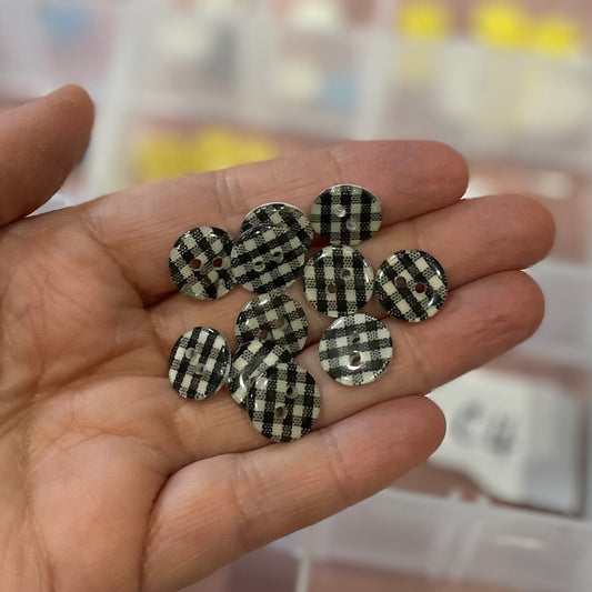 Hand holding black and white checkered buttons with a blurred background