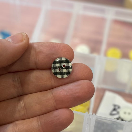 Small checkered button held between fingers with a blurred background
