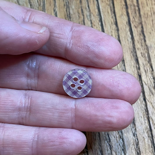 Small button held between fingers on a wooden surface