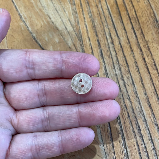 Small round button held between fingers on a wooden surface