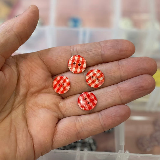 Hand holding four red and white checkered buttons with a blurred background