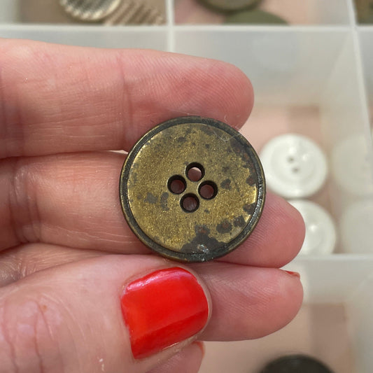Hand holding a button with a button collection box in the background