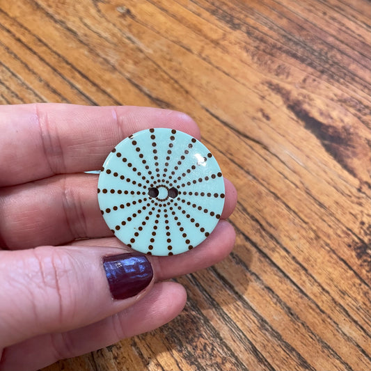 Circular object with a pattern held by a hand on a wooden surface