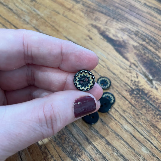 Hand holding a decorative button with more buttons on a wooden surface