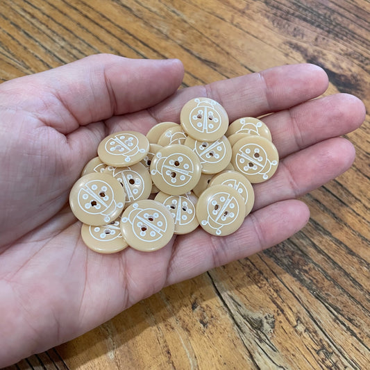 Hand holding a small pile of decorative buttons on a wooden surface