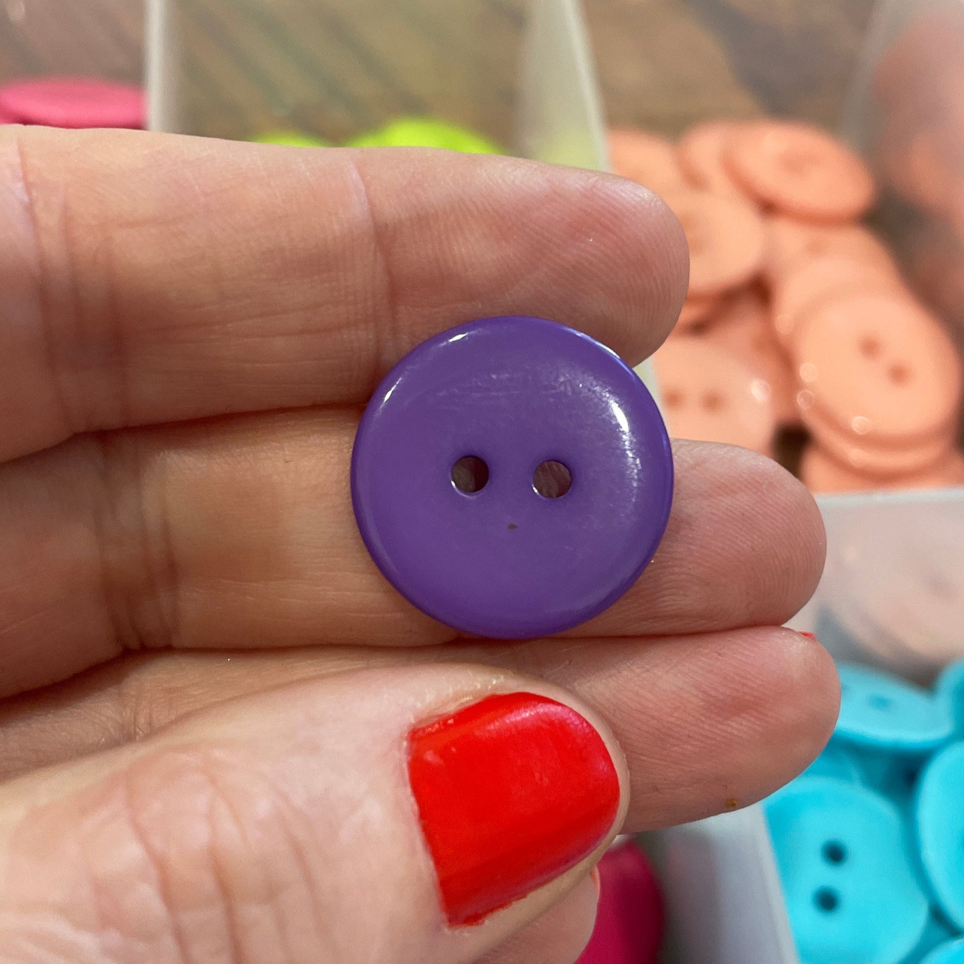 Hand holding a purple button with a background of colorful buttons