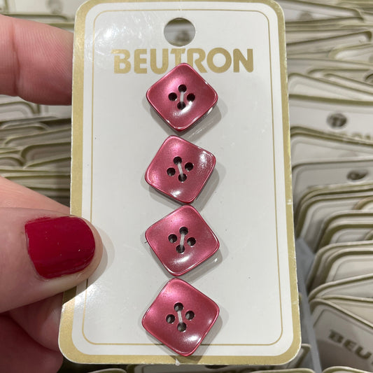 Pink buttons on a Beutron branded card held by a hand with red nail polish.