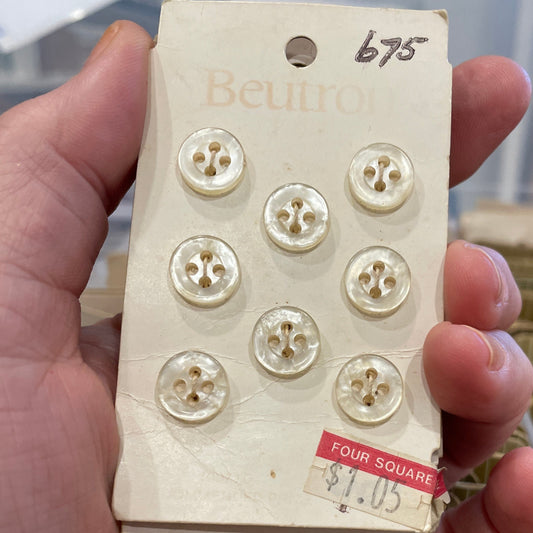 Hand holding a vintage button box with buttons on a blurred background