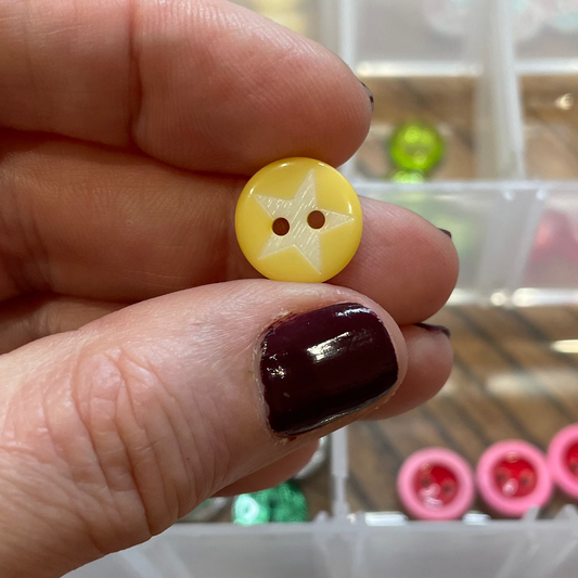Hand holding a yellow button with a grid of buttons in the background