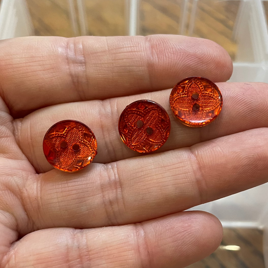 Hand holding buttons with a clear box of buttons in the background