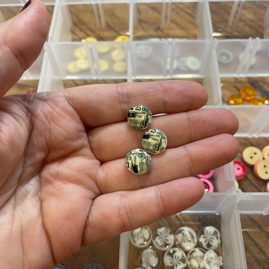 Hand holding decorative buttons with a clear container of buttons in the background
