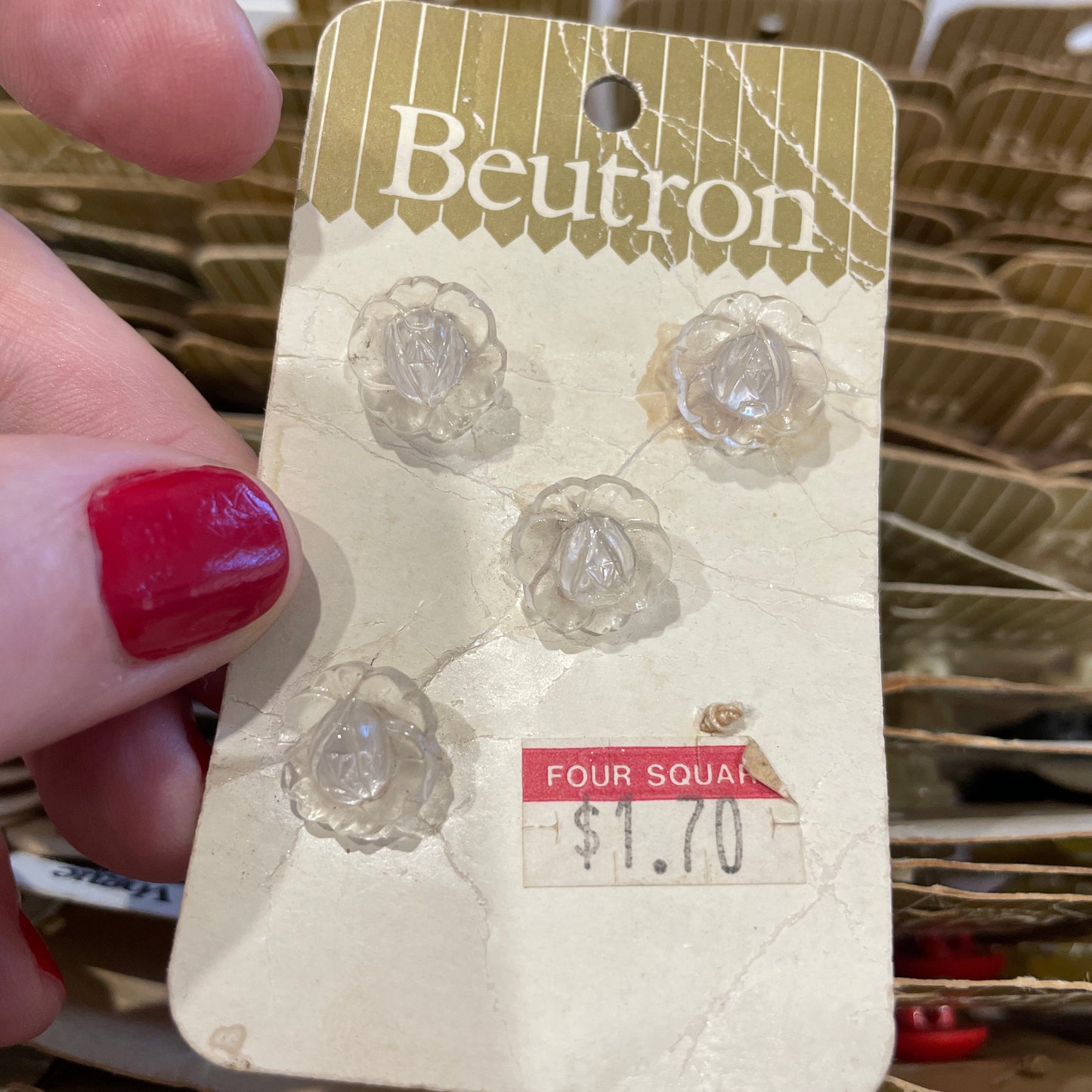 Beutron buttons  product tag held by a hand with red nail polish
